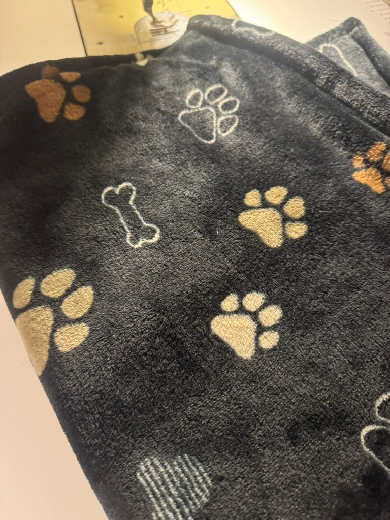 Copertina in morbido pile fondo nero e zampette e disegni marrone